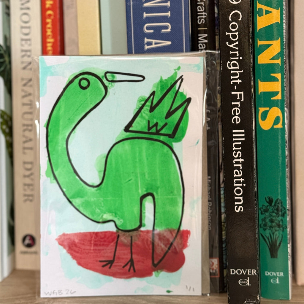 Book with a green bird illustration on a shelf with other books.