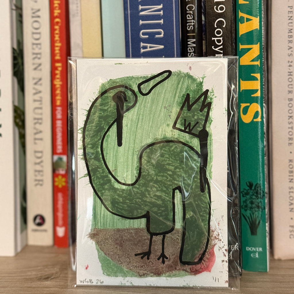 Card with a green dinosaur illustration on a bookshelf with various books.