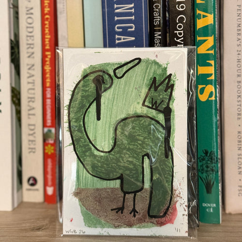 Card with a green dinosaur illustration on a bookshelf with various books.