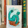 Book with a green dinosaur illustration on a shelf with other books