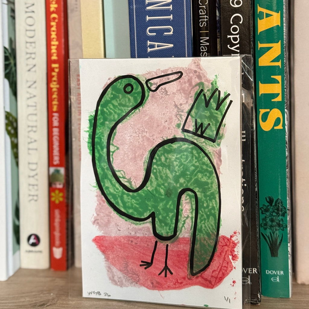 Book with a green dinosaur illustration on a shelf with other books