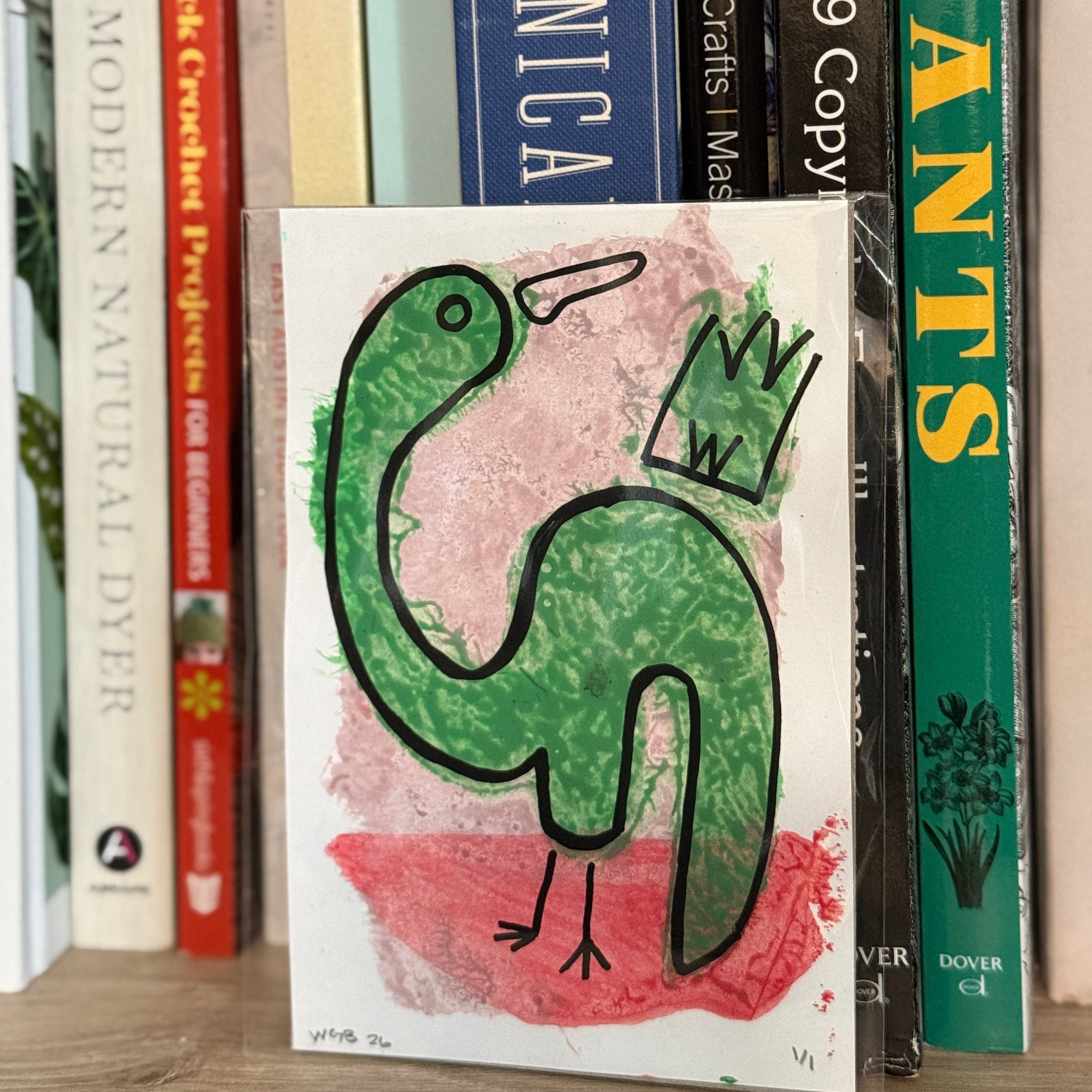 Book with a green dinosaur illustration on a shelf with other books
